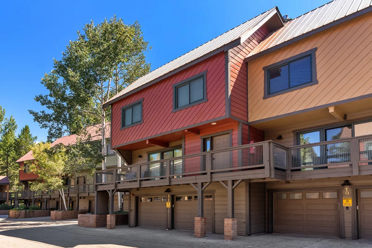 This exterior image showcases the colorful façades and balconies of Waterford 11, framed by surrounding trees. The scenery conveys a lively, inviting neighborhood atmosphere perfect for group gatherings, relaxation, and winter fun.