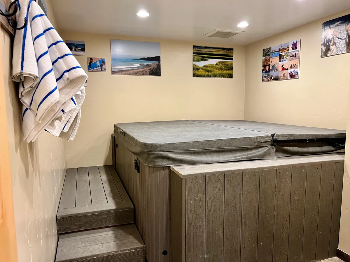 An inviting hot tub with wall decor and plush towels, set in a tranquil indoor space. The mood is calm and rejuvenating, ideal for unwinding after a day of mountain adventure or swimming in the community pool. This space suggests exclusive wellness amenities for residents.